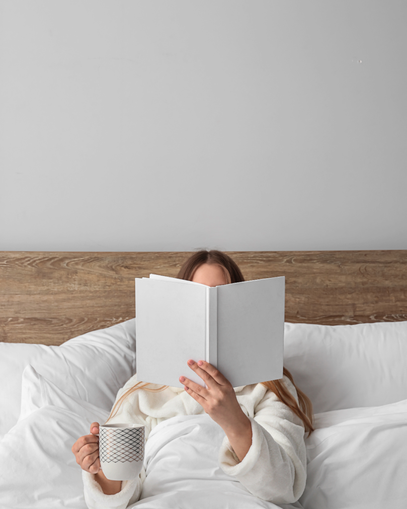 Woman reading in bed and holding a mug