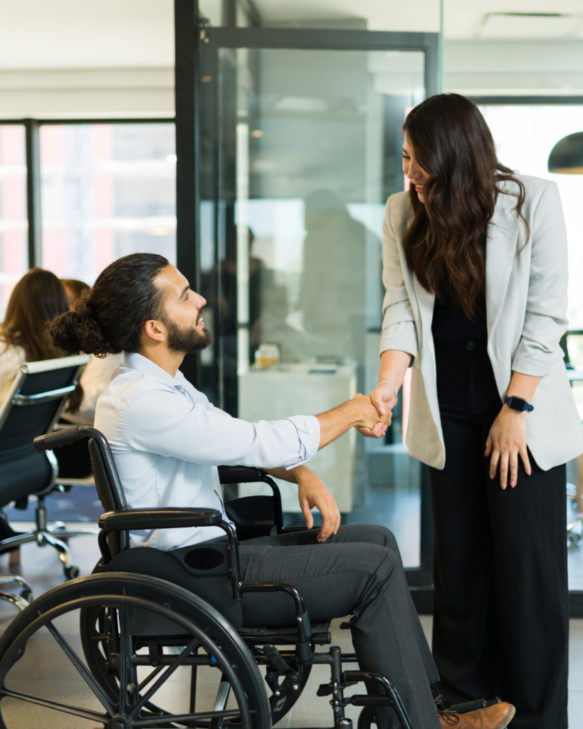 Two work colleagues shaking hands - one is in a wheelchair